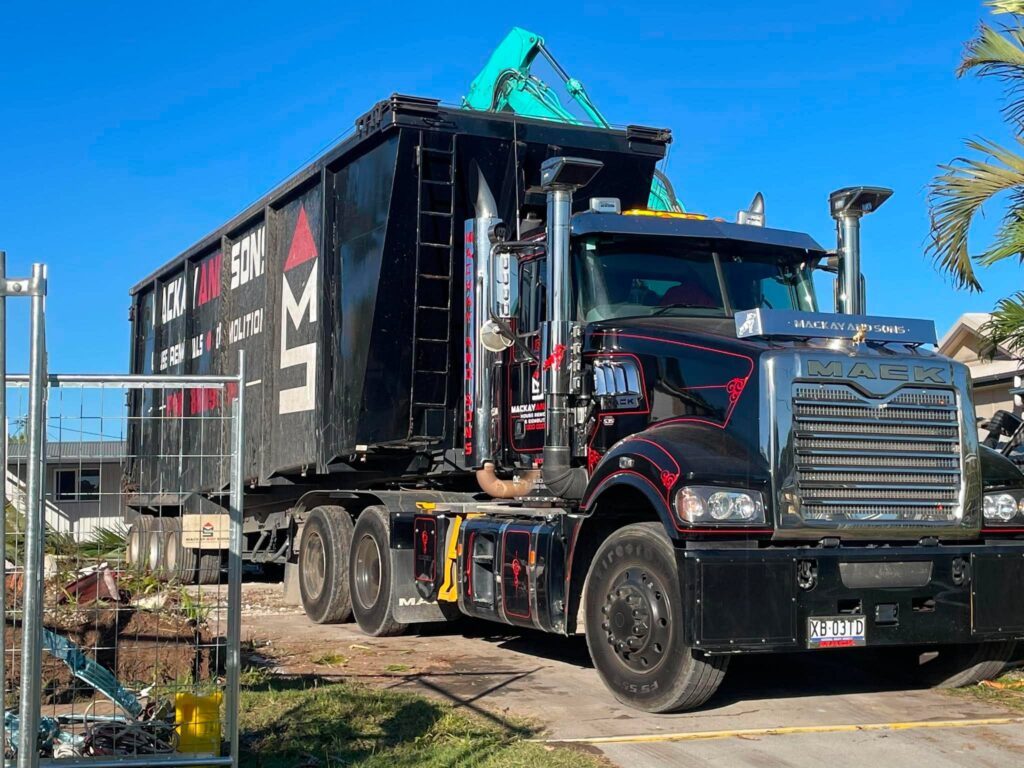 Mackay and Sons truck carrying a skip bin on a demolition site, used for asbestos and house demolition in Queensland