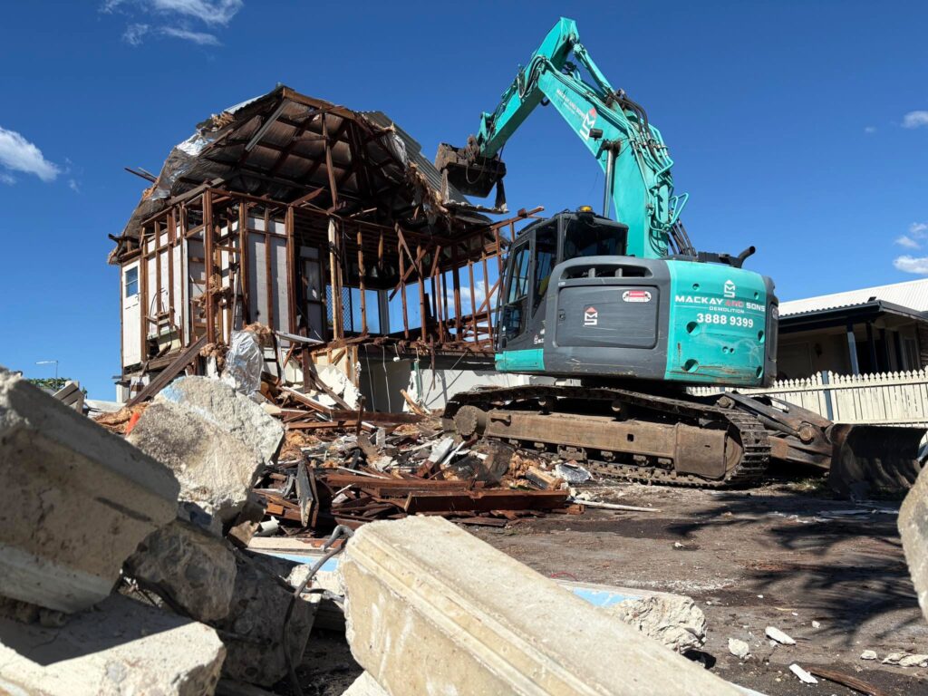 Excavator clearing a partly demolished timber house on a Queensland site